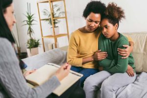 parent holding child as they talk to a therapist about the link between childhood trauma and PTSD