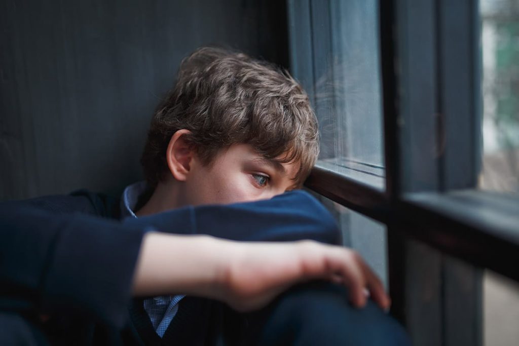 a teen's co-occurring disorder causing him sadness as he looks out a window