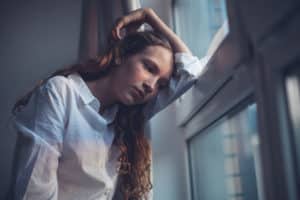 a depressed teen stares blankly out of a window