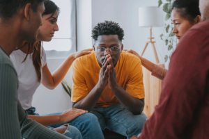 a teen is supported by peers in group therapy as part of a mental health treatment program