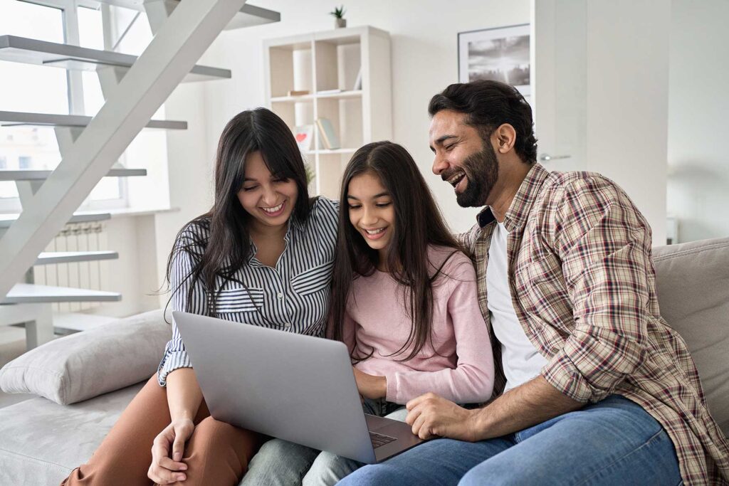 Happy family watching funny videos on a laptop together while working to improve communication