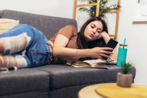 Teenager lying on couch spending too much time on her phone unaware of how social media affects mental health
