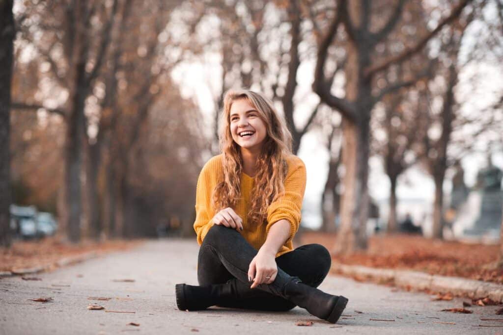 teen sitting in park on a beautiful autumn day participating in self-care fall activities