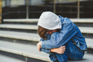 young person wearing all denim sitting on outdoor steps holding knees and curling into a ball while in need of tips to combat depression