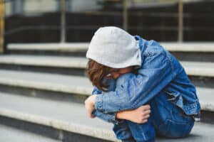 young person wearing all denim sitting on outdoor steps holding knees and curling into a ball while in need of tips to combat depression