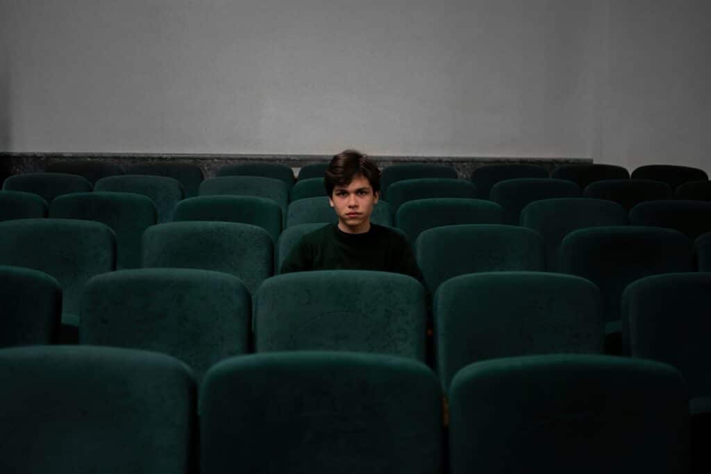 boy in blue shirt sitting in empty theater