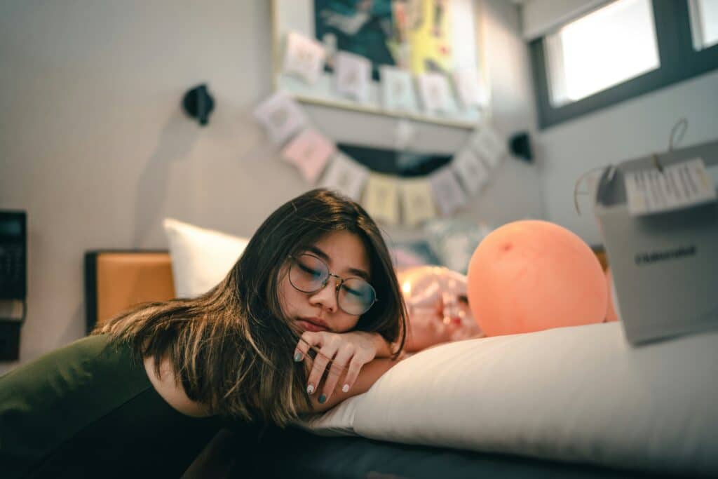 teen girl leaning on her bed closing her eyes bored