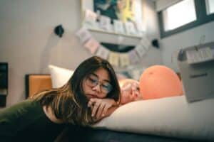 teen girl leaning on her bed closing her eyes bored