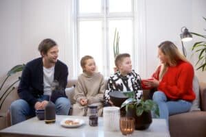 parents sitting with teens on couch the mom is talking with coffee table in front of them
